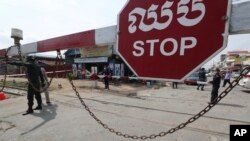 Local police officers stand guard at a blocked street near Phnom Penh International airport in Phnom Penh, Cambodia, Thursday, April 15, 2021. (AP Photo/Heng Sinith)