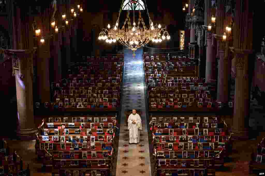 Abbot Vincent Marville stands in the central aisle of the Basilica of Neuchatel, Switzerland, which displays the portraits of 400 parishioners unable to attend the Mass due to the COVID-19 outbreak.