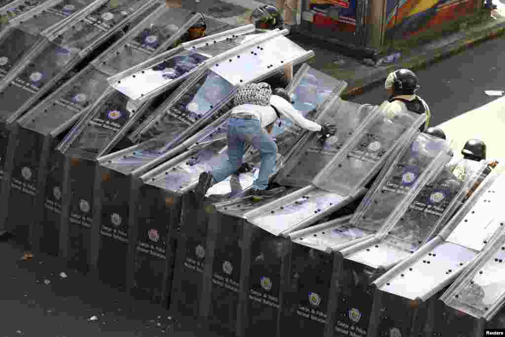 A demonstrator jumps on a shield wall formed by riot police during a protest against Venezuela&#39;s President Nicolas Maduro&#39;s government in Caracas, Feb. 12, 2014.