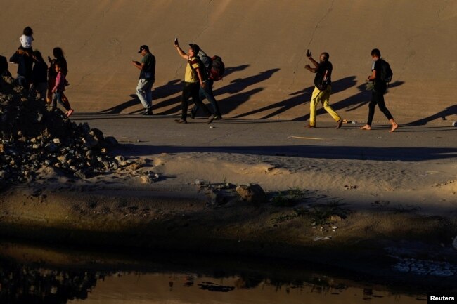 Asylum-seeking migrants, mostly from Venezuela, make videos of themselves and celebrate after crossing the Rio Grande to El Paso, Texas, U.S., as seen from Ciudad Juarez, Mexico, September 19, 2022. (REUTERS/Paul Ratje)