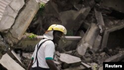 Un pompier parmi les décombres après qu'un immeuble de deux étages se soit effondré dans le district d’Utako, à Abuja, le 18 octobre 2013.