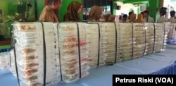 Wadah dan sisa makanan yang dikumpulkan setelah dikonsumsi para siswa, selanjutnya akan diambil penyedia makanan. (Foto: Petrus Riski-VOA)