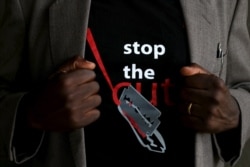 FILE - A man shows the logo of a T-shirt that reads "Stop the Cut" referring to Female Genital Mutilation during a social event advocating against harmful practices such as FGM at the Imbirikani Girls High School in Imbirikani, Kenya, April 21, 2016.