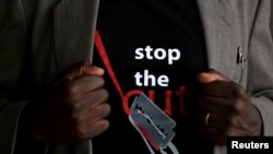 FILE - A man shows the logo of a T-shirt that reads "Stop the Cut" referring to female genital mutilation, during an event advocating against harmful practices such as FGM at the Imbirikani Girls High School in Imbirikani, Kenya, April 21, 2016.