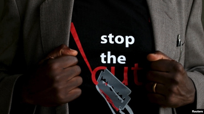 FILE - A man shows the logo of a T-shirt that reads "Stop the Cut" referring to female genital mutilation, during an event advocating against harmful practices such as FGM at the Imbirikani Girls High School in Imbirikani, Kenya, April 21, 2016.