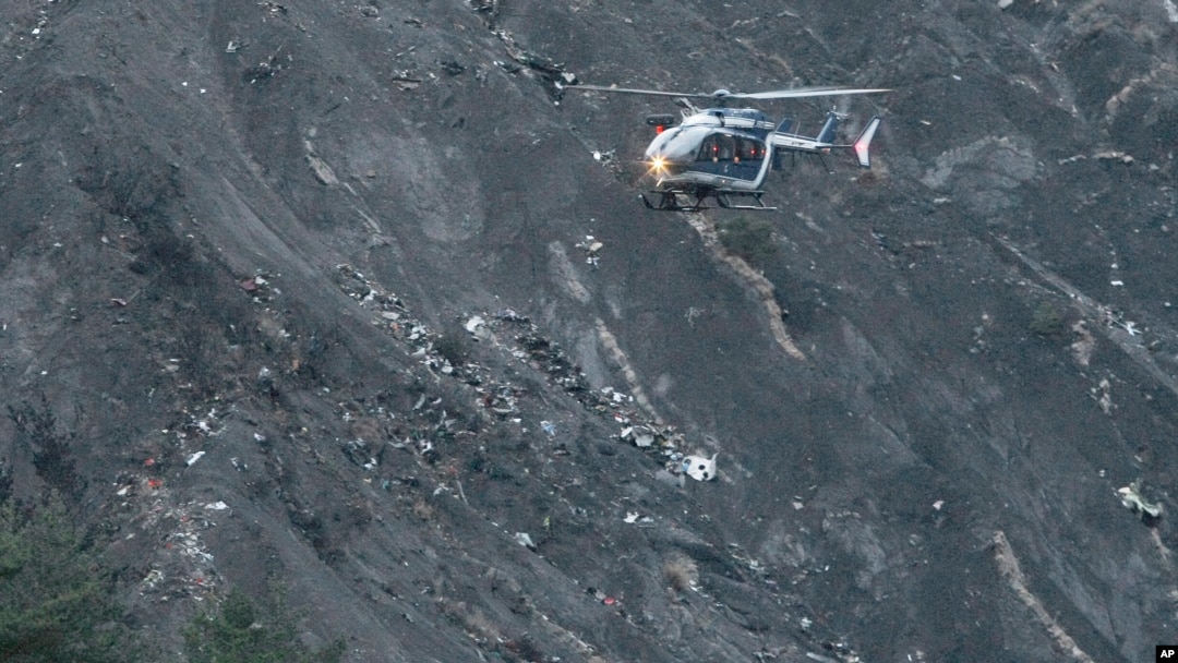 A rescue helicopter flies over debris of the Germanwings passenger jet, scattered on the mountain side, near Seyne les Alpes, French Alps, March 24, 2015. 