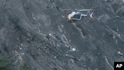 Sebuah helikopter terbang di atas reruntuhan pesawat penumpang Germanwings yang hancur di sebuah sisi gunung dekat pegunungan Alpen, Perancis, 24 Maret 2015 (AP Photo/Claude Paris) 