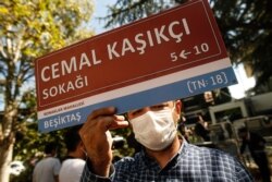 A man, holding an unofficial street sign reading in Turkish: 'Jamal Khashoggi Street,' participates in an event near the Saudi Arabia consulate in Istanbul, marking the two-year anniversary of his death, Oct. 2, 2020.