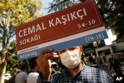 A man, holding an unofficial street sign reading in Turkish: 'Jamal Khashoggi Street,' participates in an event near the Saudi Arabia consulate in Istanbul, marking the two-year anniversary of his death, Oct. 2, 2020.