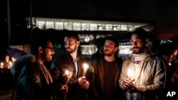 Demonstrators hold candles during a gathering in front of the Acropolis museum at the foot of the Acropolis hill in Athens, Sunday Jan. 18, 2015.