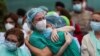 FILE - Health workers wearing protective face masks react during a tribute for their co-worker Esteban, a male nurse who died of complications related to COVID-19, outside the Severo Ochoa Hospital in Leganes, Spain, April 13, 2020.
