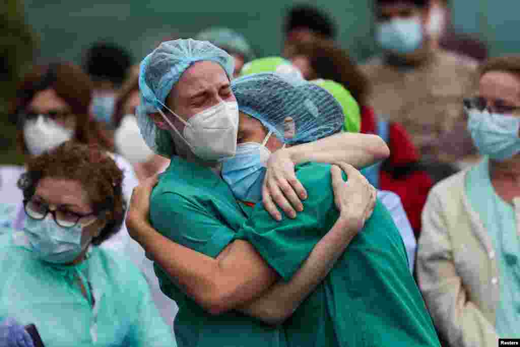 FILE - Health workers wearing protective face masks react during a tribute for their co-worker Esteban, a male nurse who died of complications related to COVID-19, outside the Severo Ochoa Hospital in Leganes, Spain, April 13, 2020.