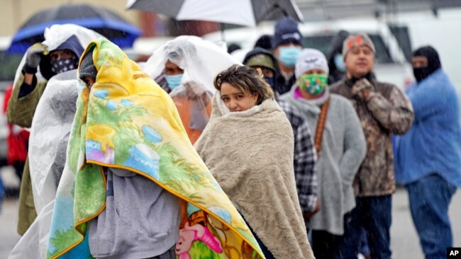 FILE - People wait in line to fill propane tanks in Houston, Texas, Feb. 17, 2021. Millions in the state had no power after a historic snowfall and freezing temperatures created a surge of demand for electricity the power grid could not provide.