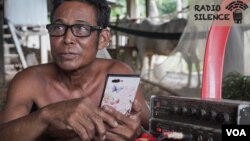 Khon Kheap, a resident in Prey Veng province, sits next to an amplifier connected to a loudspeaker which he uses to tune in to news broadcasts and play out loud for his fellow villagers. (Khan Sokummono/VOA Khmer)