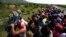 A man holds up a stroller as hundreds of migrants hitching a ride accommodate themselves on the back of truck, between Niltepec and Juchitan, Mexico, Oct. 30, 2018.