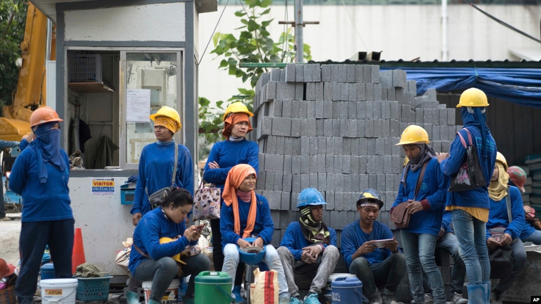 FILE - Cambodian migrant construction workers wait for their transport home outside a building site in downtown Bangkok, Thailand.