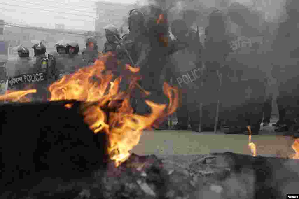 Police stand guard near tyres set on fire by activists of Bangladesh Nationalist Party (BNP) during a nationwide blockade in Dhaka December 9, 2012. Police fired rubber bullets and tear gas to disperse protesters staging blockades across Bangladesh on Sun