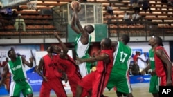 FILE - A player from Kano Pillars, center, in green and white, jumps to make a basket, challenged by Mark Mentors players in red and black, during Nigeria's Final Four in Lagos, Nigeria, Sept. 5, 2013.