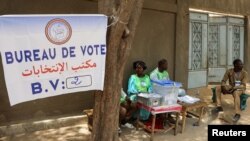 Les travailleurs électoraux s'assoient à côté d'une urne dans un bureau de vote lors de l'élection présidentielle à N'djamena, au Tchad, le 6 mai 2024.