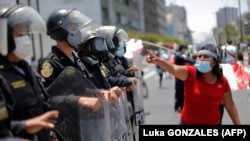 Une femme exprime ses sentiments devant la police à l'extérieur du Congrès à Lima après que le président intérimaire du Pérou, Manuel Merino, a présenté sa démission le 15 novembre 2020.