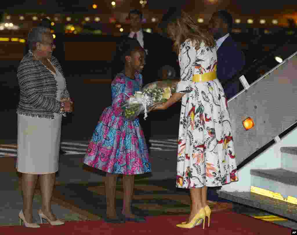 Melania Trump recebida por uma menina com flores e pela primeira-dama do Quénia, Margaret Kenyatta, no Aeroporto Internacional Jomo Kenyatta em Nairobi, Quénia. 4 de Outubro, 2018.