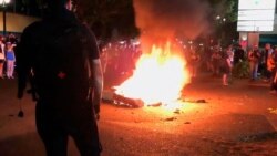In this image taken from video a mattress burns in the street near the Portland Police Bureau's North Precinct, Sept. 6, 2020, in Portland, Ore.