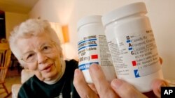 FILE - Ruth Ronk holds some of the medications she has purchased from Canada, in her Appleton, Wis. home.