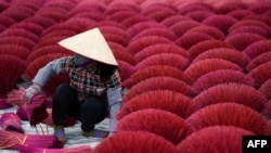 A Vietnamese woman collects dried incense sticks in a courtyard in the village of Quang Phu Cau on the outskirts of Hanoi, Jan. 3, 2019.