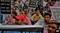 FILE - Sewer cleaning workers and others sit during a protest near the Indian parliament calling for safer working conditions following the deaths of several sanitation employees, in New Delhi, India, Sept.25, 2018.