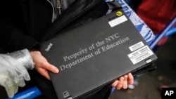 Anna Louisa, 18, receives her school laptop for home study at the Lower East Side Preparatory School Thursday, March 19, 2020, in New York, as coronavirus restrictions shuttered classrooms throughout the city.