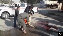 Locals sweep blood at the site of a gun attack on a Japanese aid worker's truck, Dec. 4, 2019, Nangarhar province, eastern Afghanistan. 
