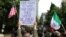 Protesters hold signs as they face off in Portland. (R. Taylor/VOA)