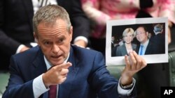 Pemimpin partai oposisi Bill Shorten memegang foto Menteri Luar Negeri Julie Bishop bersama pengusaha Cina Huang Xiangmo dalam sesi Tanya Jawab di gedung parlemen di Canberra, Australia, 14 Juni 2017. (Foto: dok).