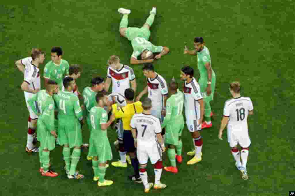 Referee Sandro Ricci from Brazil, center, talks to the players as Algeria's Sofiane Feghouli sits on the floor during the World Cup round of 16 soccer match between Germany and Algeria at the Estadio Beira-Rio in Porto Alegre, Brazil, Monday, June 30, 201
