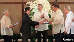 Tổng thống Philippines Benigno Aquino (giữa) hoan nghênh khi Trưởng đoàn đàm phán Mặt trận Giải phóng Hồi giáo Moro (MILF) Mohagher Iqbal (thứ 2-bên trái) bắt tay với Chủ tịch Thượng viện Franklin Drilon (thứ 2-bên phải) trong buổi lễ bàn giao dự thảo Luật cơ bản Bangsamoro (BBL).