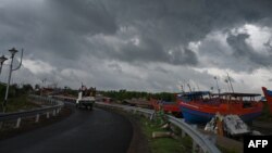 Awan gelap membayang di atas perahu nelayan yang ditambatkan, saat Topan Yaas bergerak menuju pantai timur India di Teluk Benggala. Topan Yaas diperkirakan akan mendarat di Digha sekitar 190 km dari Kolkata, 25 Mei 2021. (Foto: Dibyan gshu SARKAR / AFP)