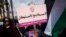 Palestinian protester holds placard with Arabic writing that says "no peace with settlements, the Palestinian Women Labor Association," anti-peace talks rally, Ramallah, March 19, 2014.