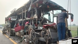 A roadside assistance worker tows away the mangled remains of a double-decker passenger bus that collided with a milk truck, near Unnao, in northern India state of Uttar Pradesh, July 10, 2024. 