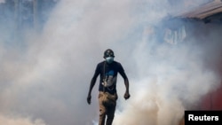 FILE - A protester walks amid smoke as supporters of Kenya's opposition leader Raila Odinga of the Azimio La Umoja, participate in an anti-government protest against the imposition of tax hikes by the government in Nairobi, Kenya July 21, 2023. 