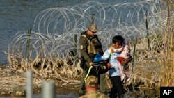 Migrantes detenidos en la frontera entre Texas y México, el miércoles 3 de enero de 2024, en Eagle Pass, Texas. (Foto AP/Eric Gay)