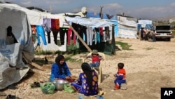 FILE - Syrian women prepare food for their family outside their tents, at a Syrian refugee camp in the town of Bar Elias, in Lebanon's Bekaa Valley, March 29, 2016. 