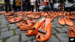 (FILE) Women's rights activists set orange pair of shoes on the pavement for every attempted or successful killing of a woman by partner violence during the International Day for the Elimination of Violence Against Women, in Cologne, Germany, Monday, Nov. 25, 2024.