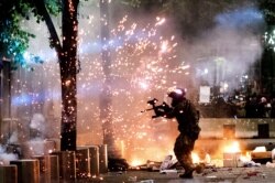 A federal officer fires crowd control munitions at Black Lives Matter protesters at the Mark O. Hatfield United States Courthouse on Friday, July 24, 2020, in Portland, Ore.