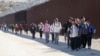 FILE - Migrants from China and elsewhere walk along a wall after crossing the U.S. border with Mexico to seek asylum, near Jacumba, California, Oct. 24, 2023.