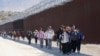 FILE - A group of people, including many from China, walk along the wall after crossing the border with Mexico to seek asylum, near Jacumba, California, Oct. 24, 2023. 