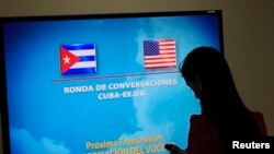 FILE - A journalist stands near a screen announcing a round of negotiations between Cuba and the U.S. in Havana, January 22, 2015.