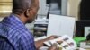 Edward Muthoka of the ICRC leafs through a photo book of registered missing persons, in Maiduguri, Nigeria. (C. Oduah/VOA)