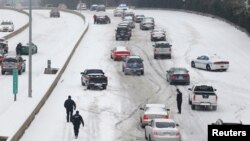 Petugas Kepolisian Charlotte Mecklenburg berupaya membantu mengarahkan para pengendara saat hendak mengemudi melewai bukit yang tertutup salju di Charlotte, North Carolina (12/2).