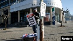 A worker hangs posters displaying newspaper headlines, in the capital Maseru, August 31, 2014.