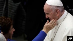 FILE - A woman reaches to touch Pope Francis during an audience at the Vatican, Nov. 30, 2018.